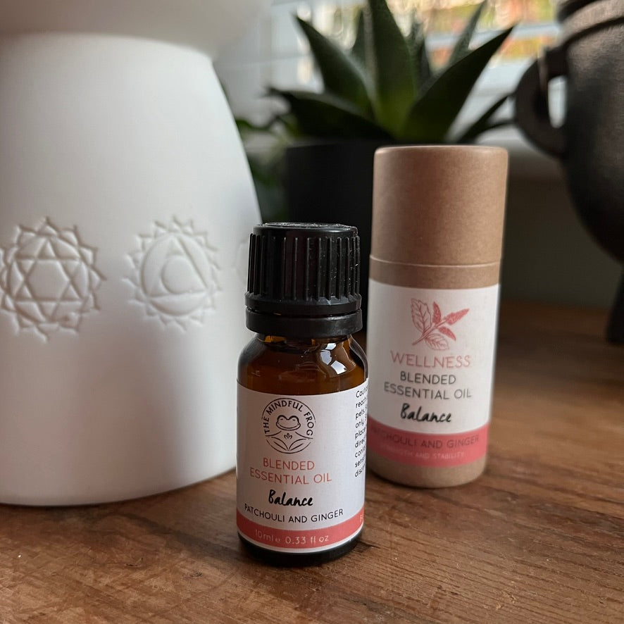 Two essential oil products on a wooden surface with a white diffuser in the background.