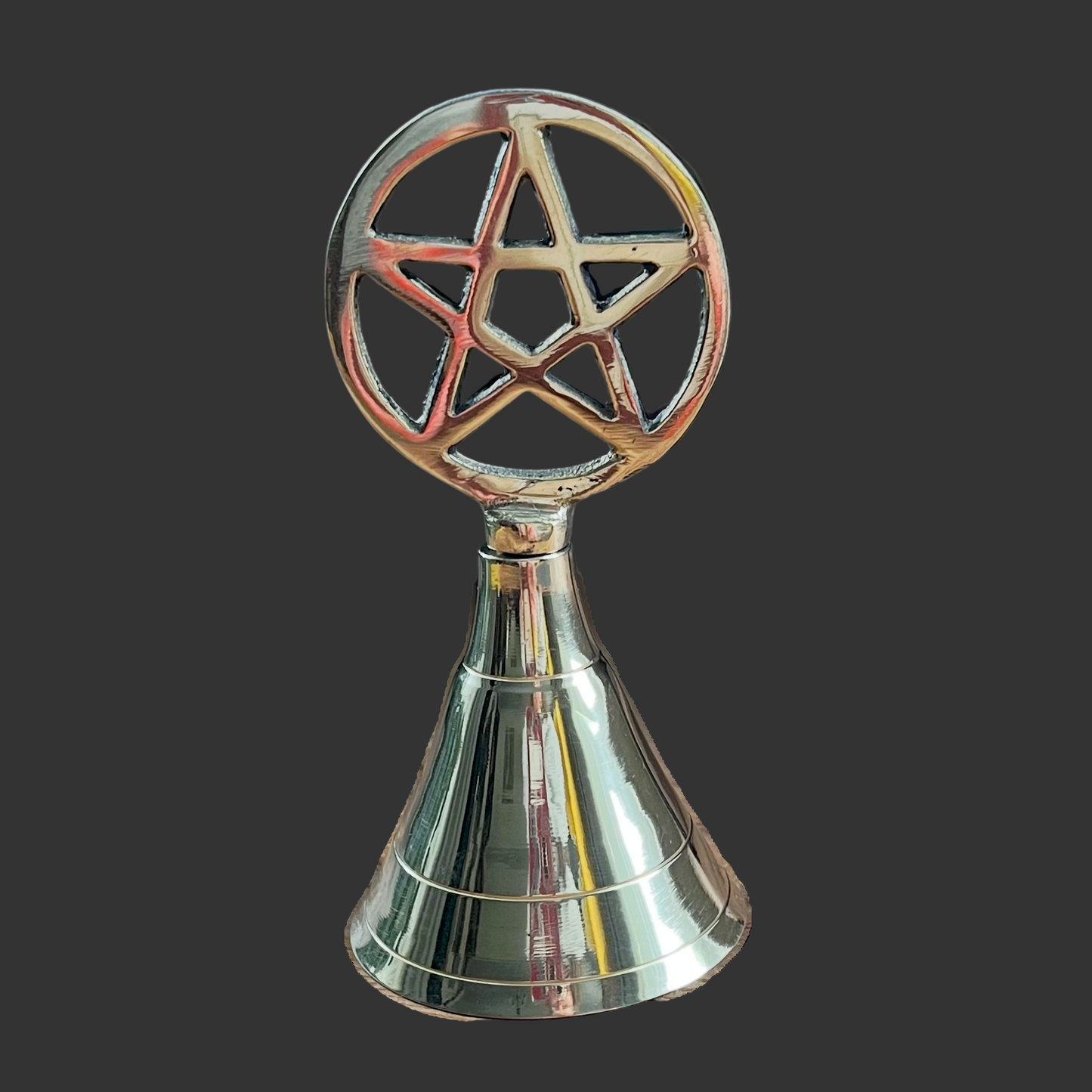 Decorative brass bell with a pentagram design on a black background