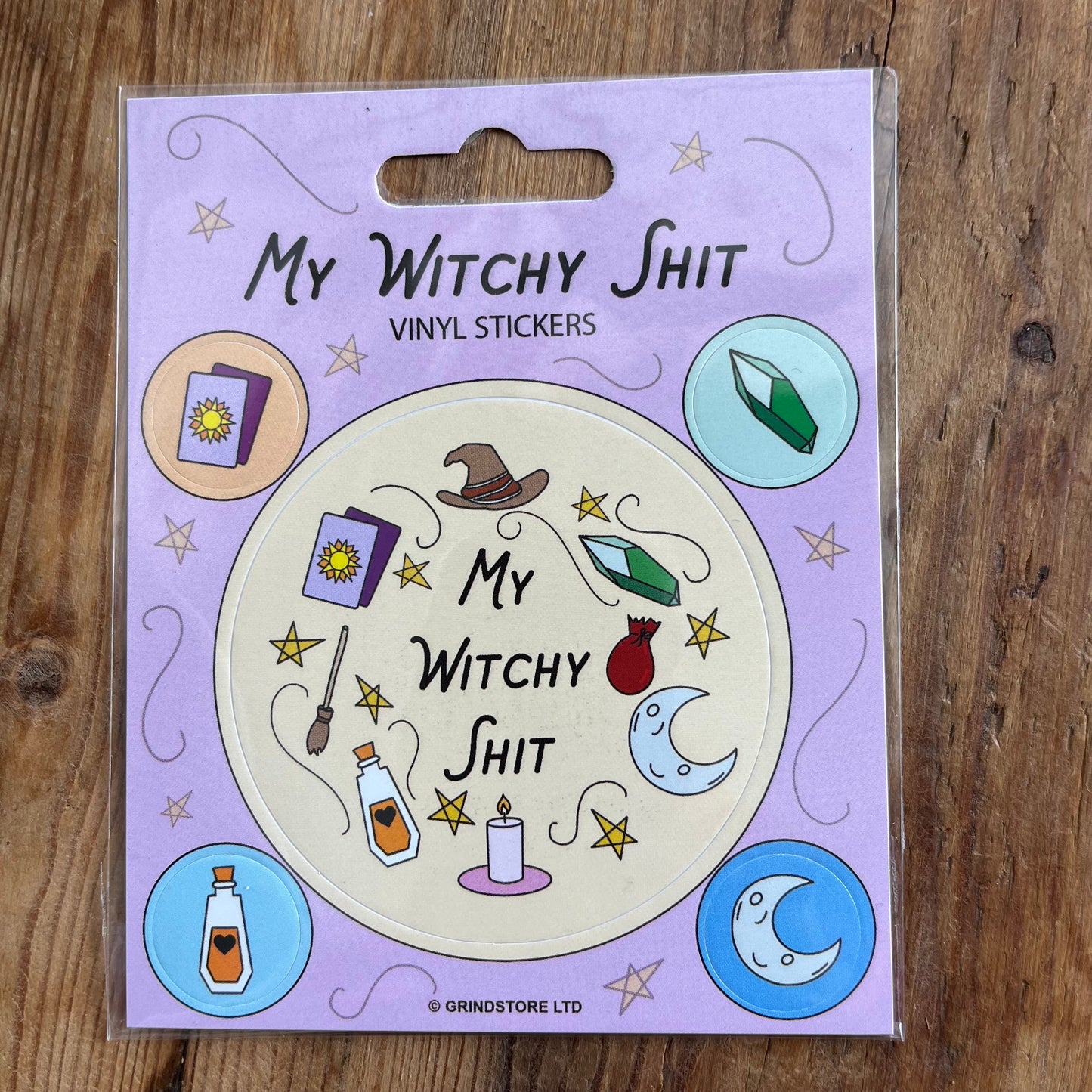 I large sticker that is illustrated with witchcraft symbols of hat, crystals, mon, candle, spell jar and besom with the words 'M Witchy Sht" 4 smaller stickers, 1 book of shadows, 1 crystal, 1 spell bottle, 1 crescent moon