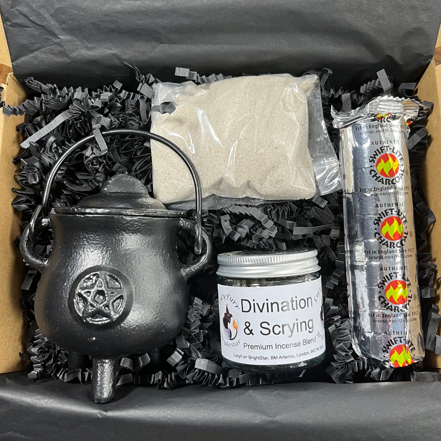 Witchcraft supply kit with black cauldron, incense, and packaging on crinkled paper