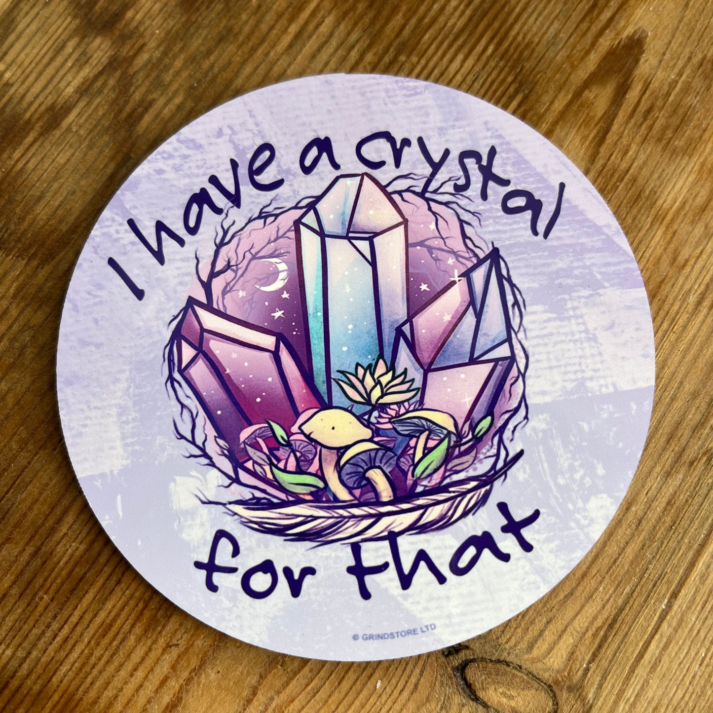 Purple coaster with an illustration of crystals and the words 'i have a crystal for that'