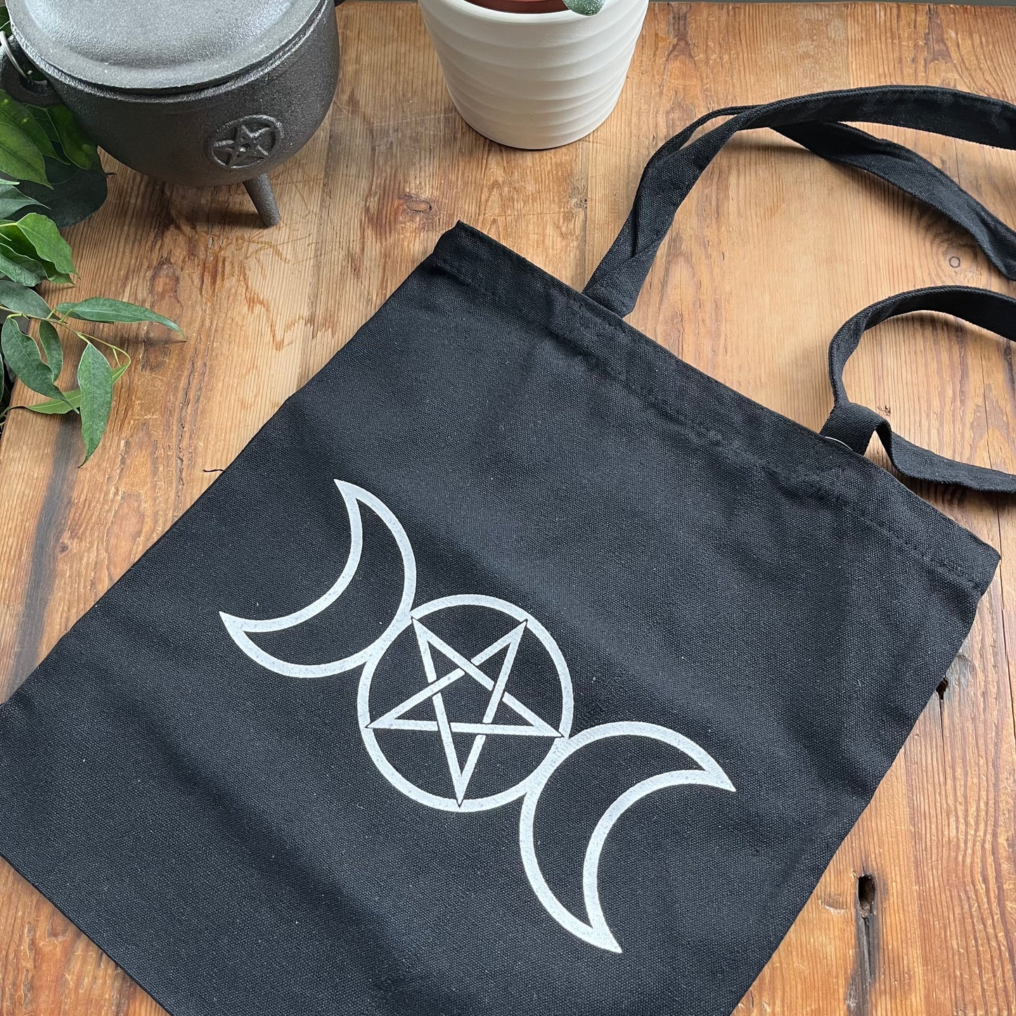 Black bag with white triple moon and pentagram symbol on a wooden table