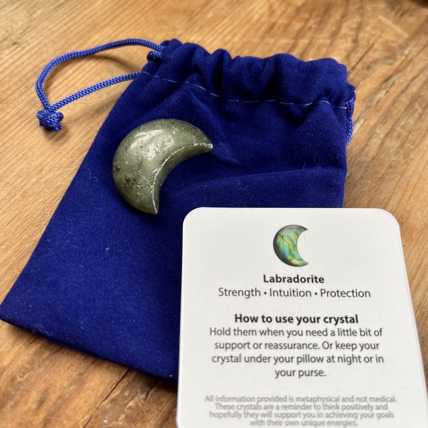 Blue velvet pouch, Labradorite crescent shaped moon and the sentiment card witch gives a description of labradorites properties and how to use.