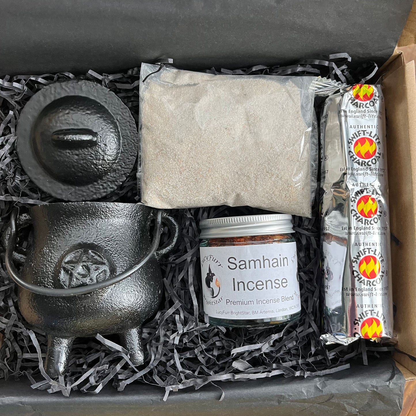 Witchcraft supply kit with black cauldron, Samhain incense, and other items in a box.