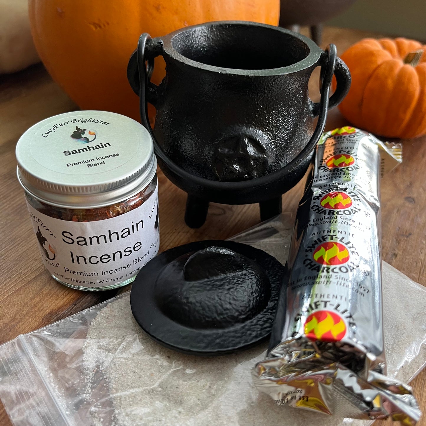 Samhain incense jar with a black cauldron and pumpkins on a wooden surface