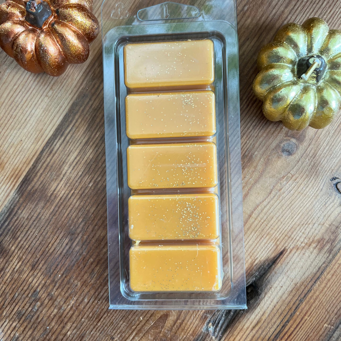 Pack of Pumpkin Spice soy wax melts on a wooden surface with decorative pumpkins.
