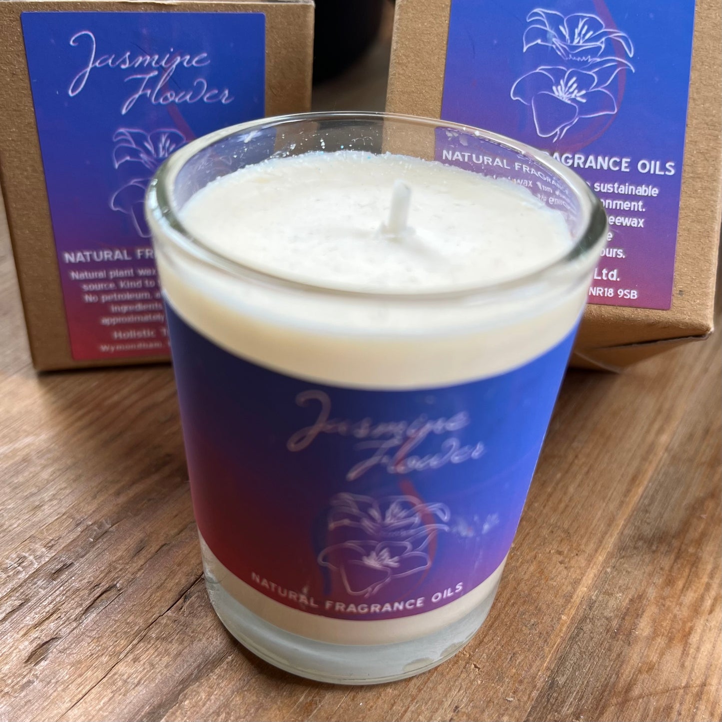 White votive candle with purple label stating it is a natural fragranced Jasmine candle