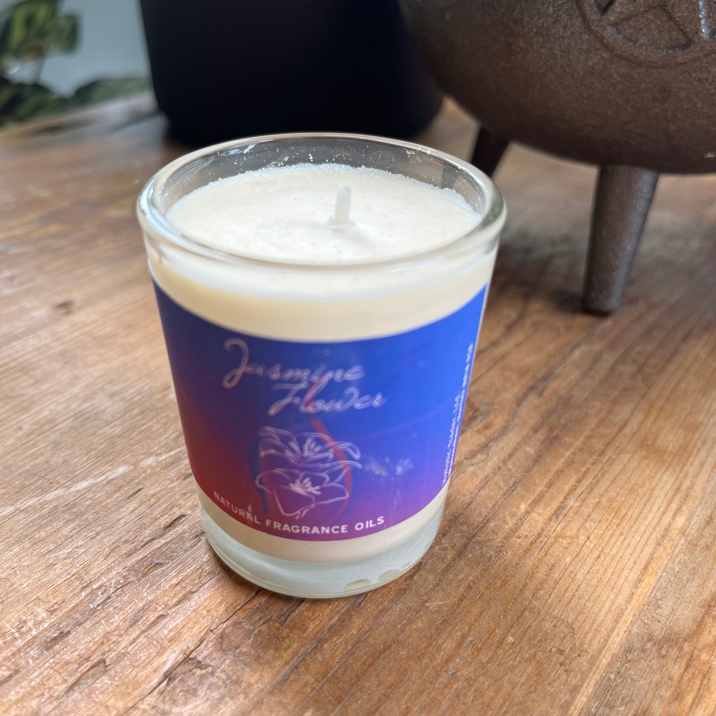 White votive candle with purple label stating it is a natural fragranced Jasmine candle