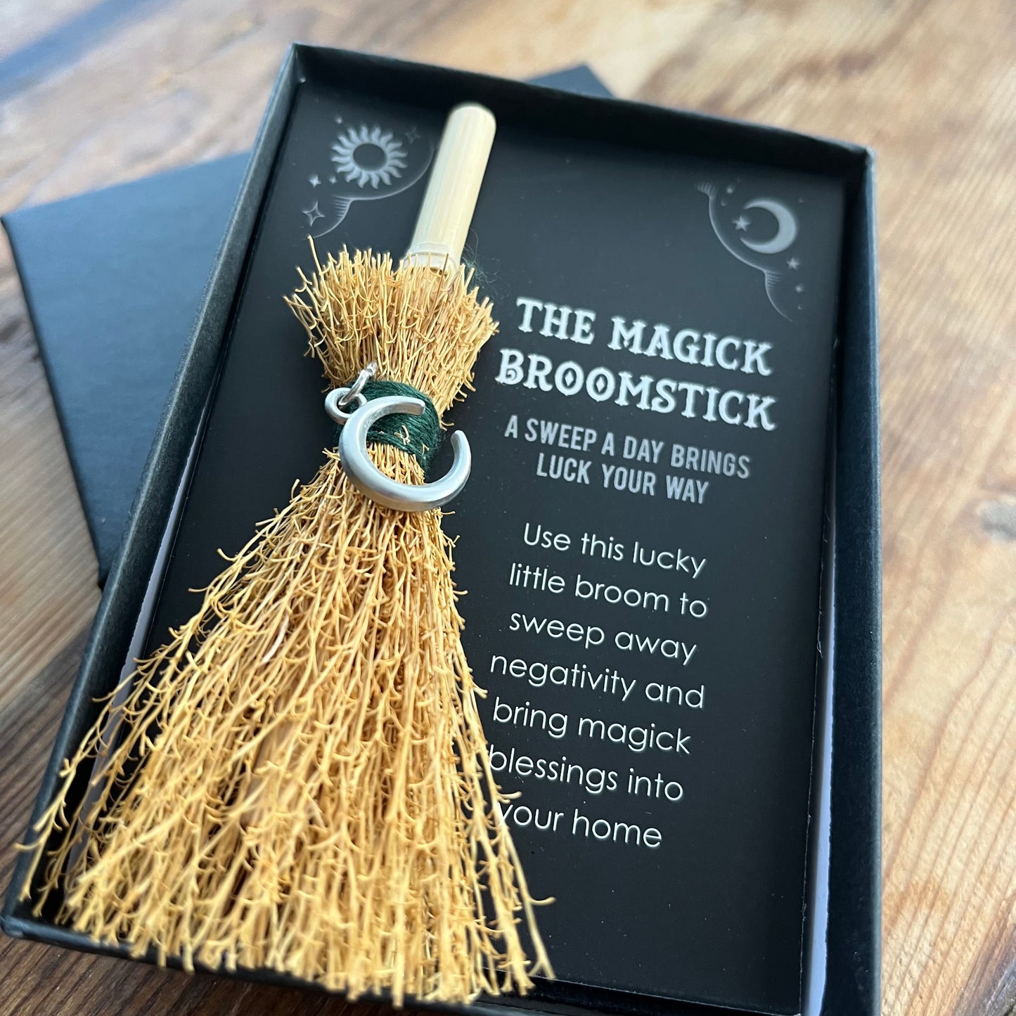 Magick broomstick with decorative text on a wooden surface