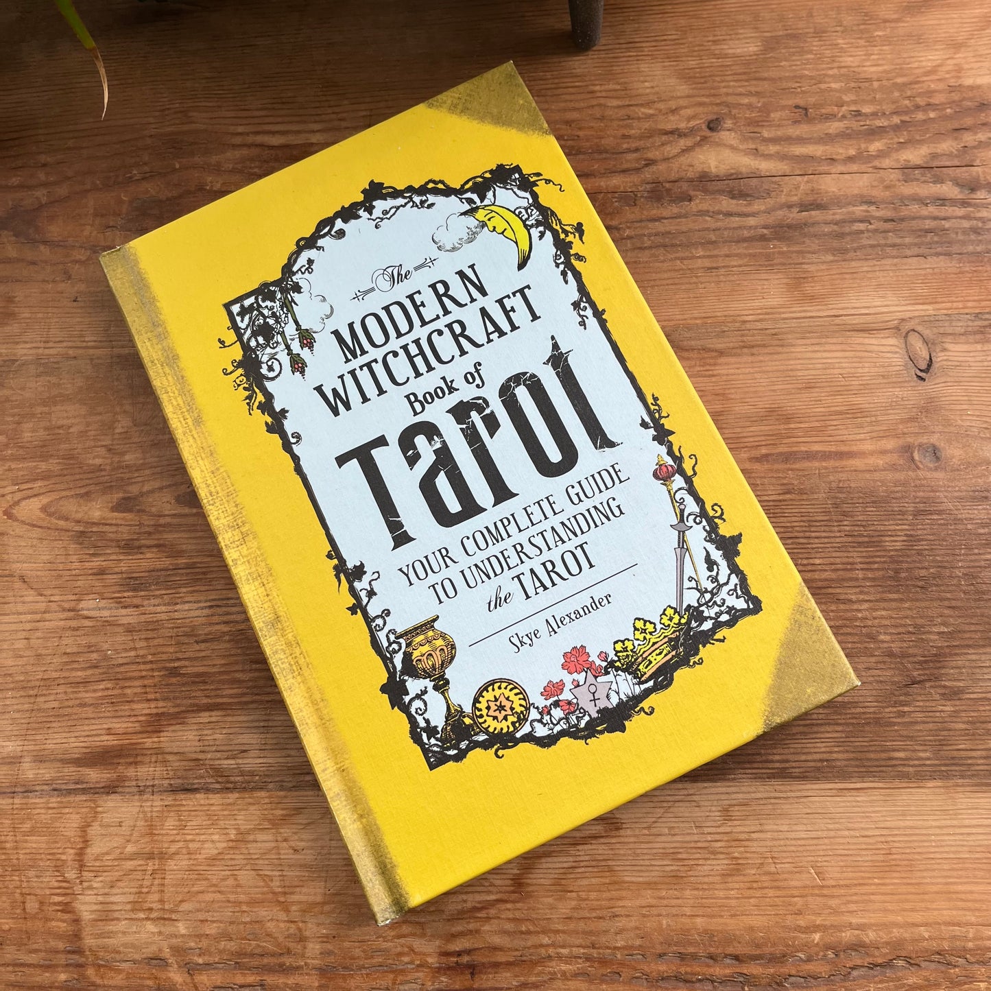Book titled 'The Modern Witchcraft Book of Tarot' on a wooden surface