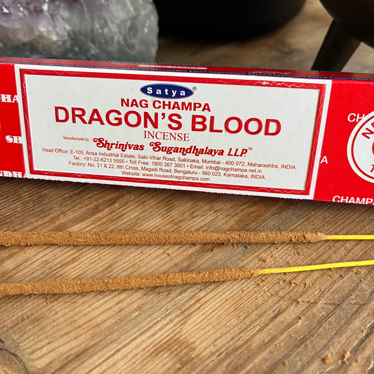 A package of Dragons Blood incense by Satya Nag Champa Incense LTD, with red and white color scheme. aongside some loose incense sticks