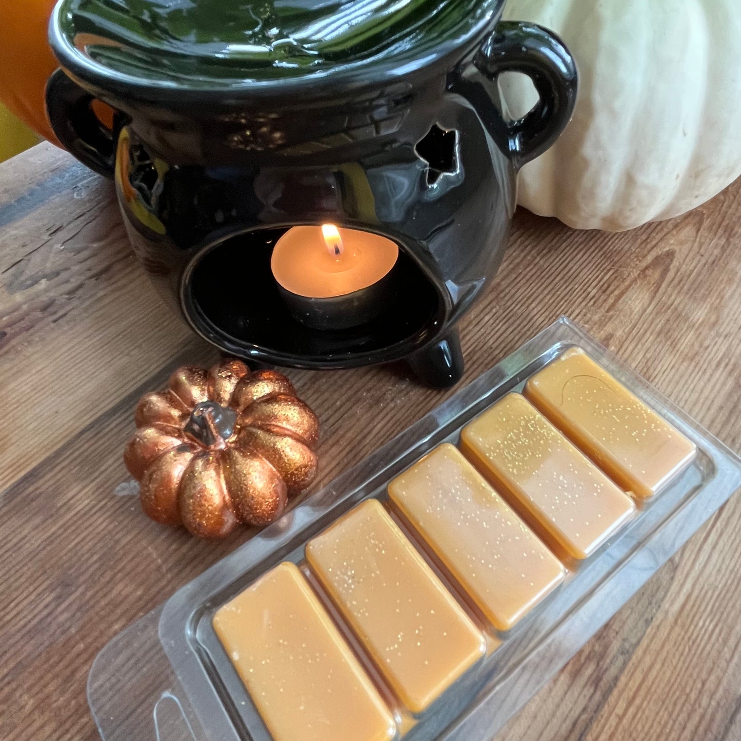 Pack of Pumpkin Spice soy wax melts on a wooden surface with decorative pumpkins.