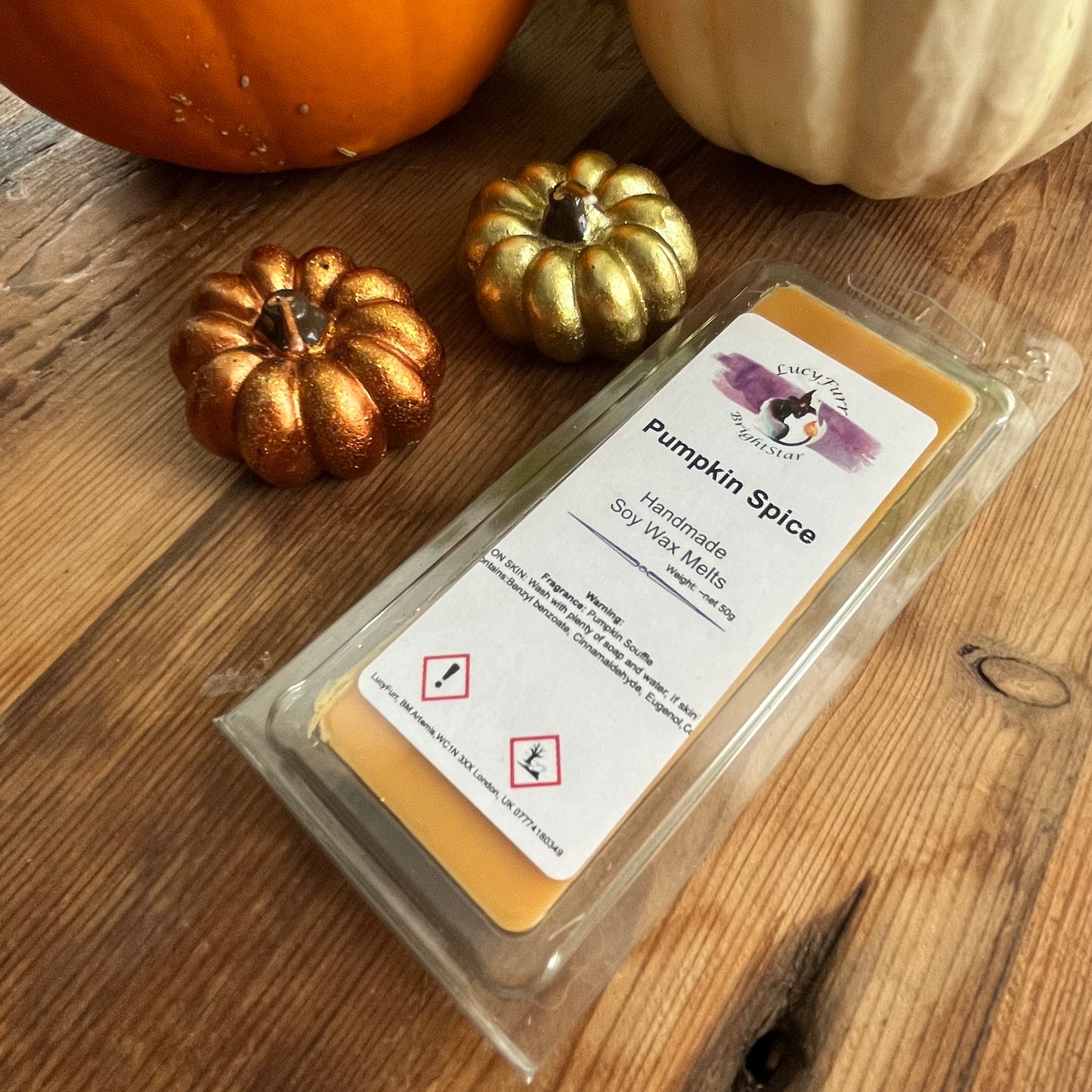 Pack of Pumpkin Spice soy wax melts on a wooden surface with decorative pumpkins.