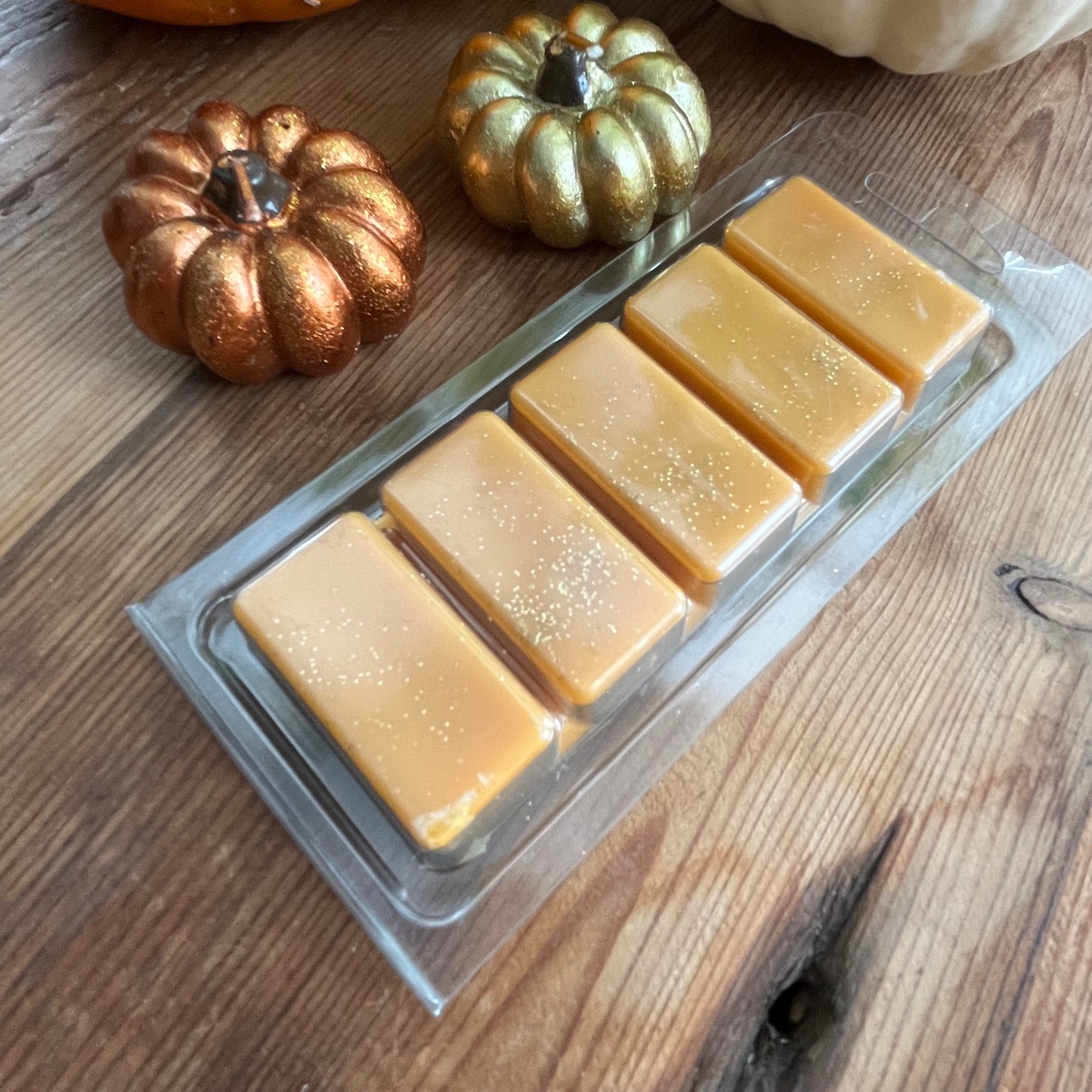 Pack of Pumpkin Spice soy wax melts on a wooden surface with decorative pumpkins.