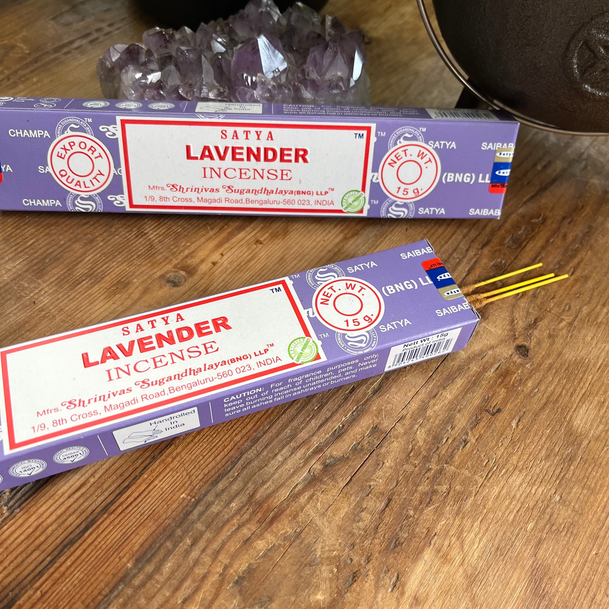 Two packages of Satya Lavender incense on a wooden surface with crystals in the background.