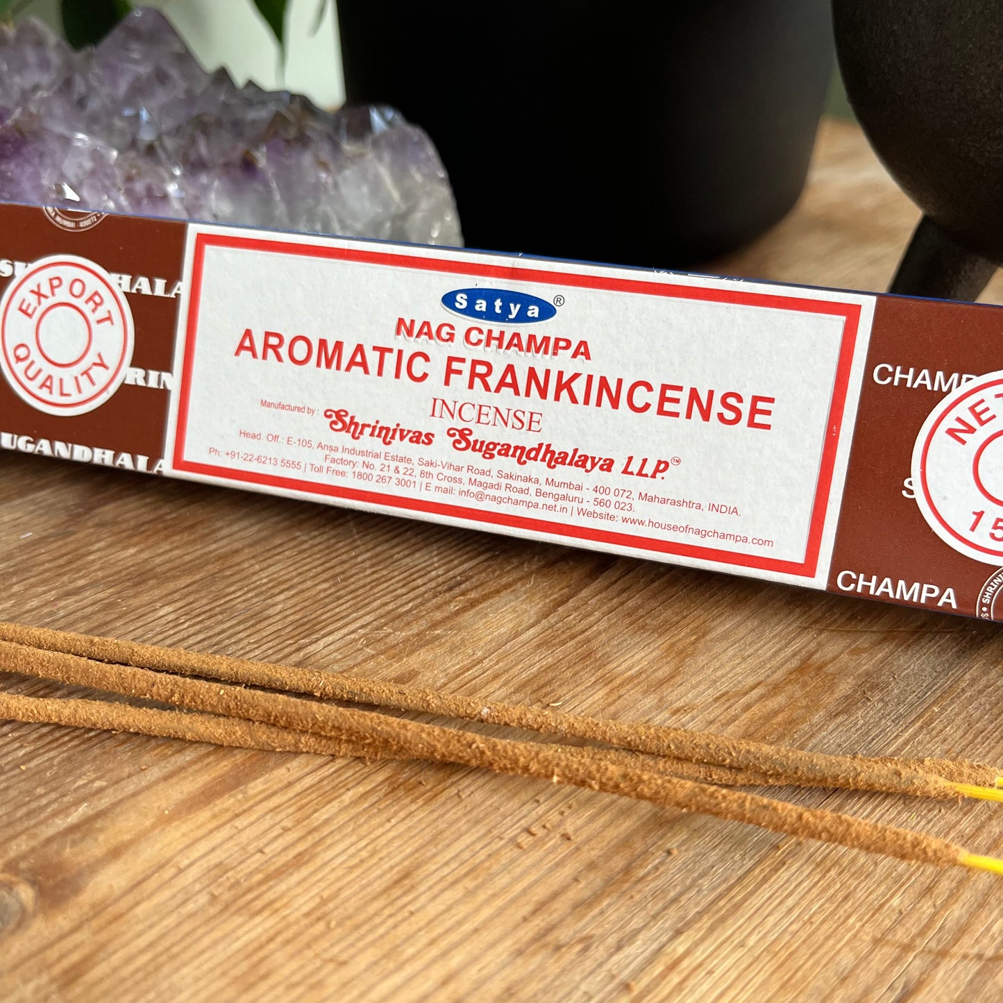 A package of Satya Nag Champa Aromatic Frankincense incense is displayed on a wooden surface.