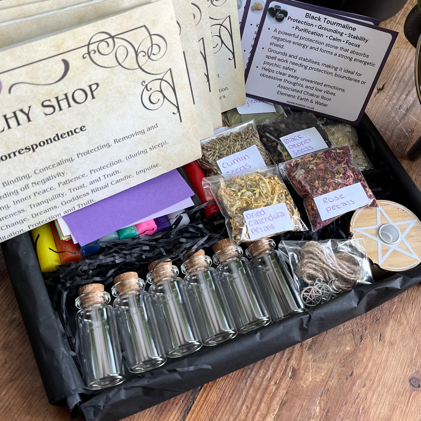 Witchy spell kit with bottles, herbs, and correspondences on a wooden surface