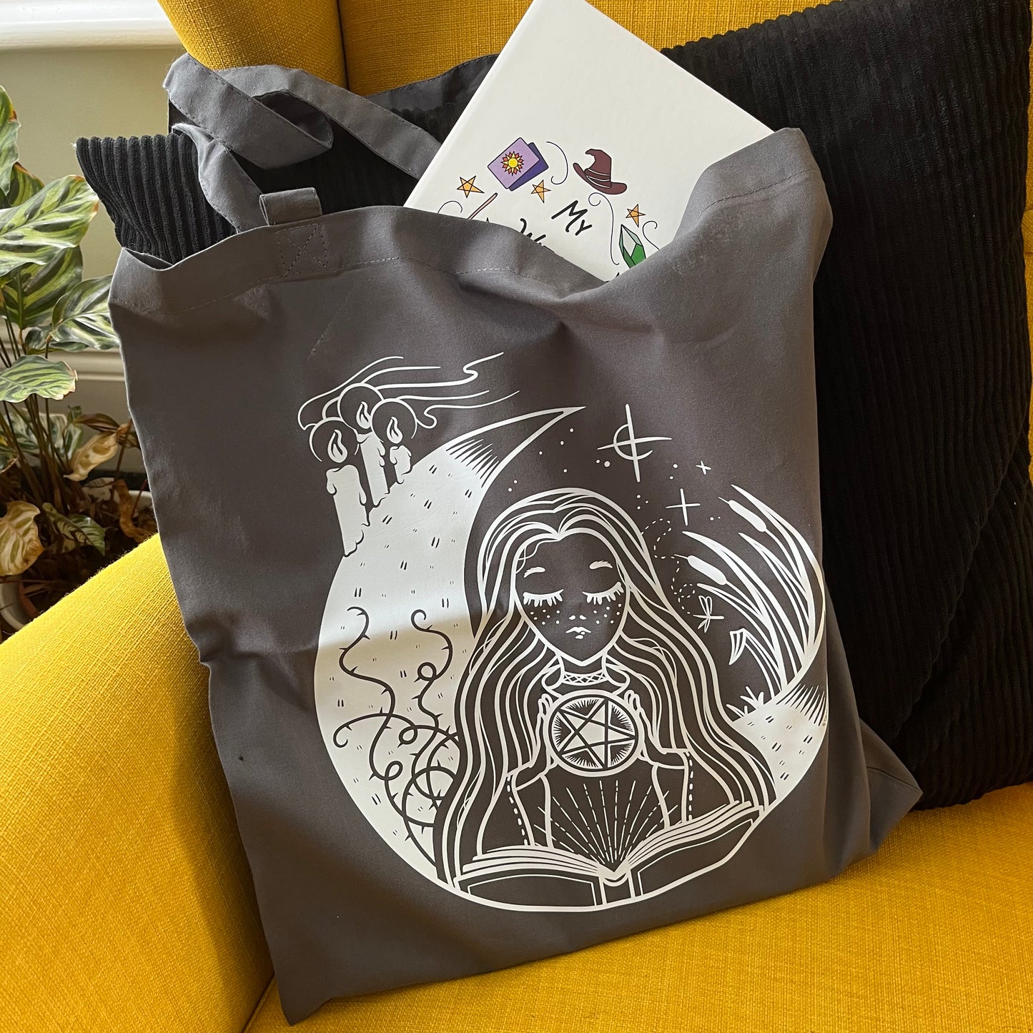 Gray tote bag with white design on a yellow couch