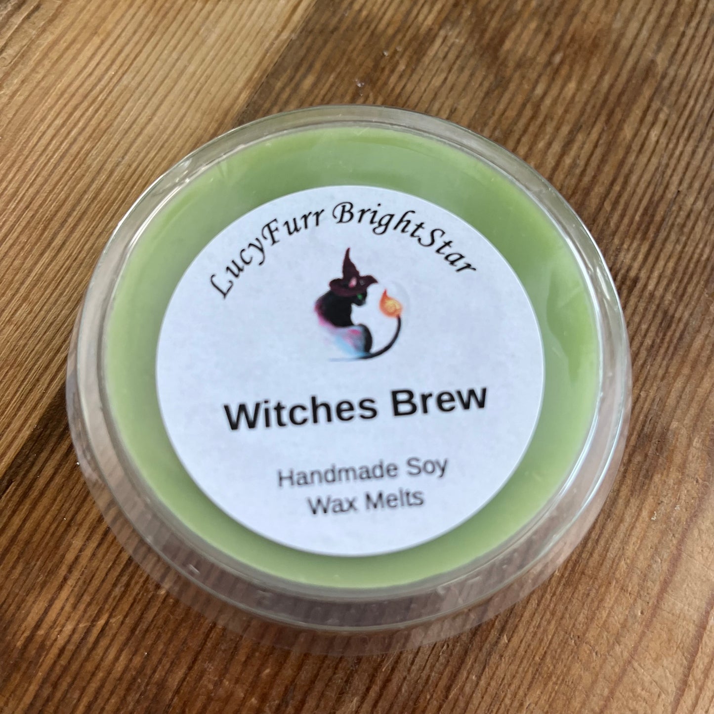 Container of 'Witches Brew' handmade soy wax melts with a label on a wooden surface