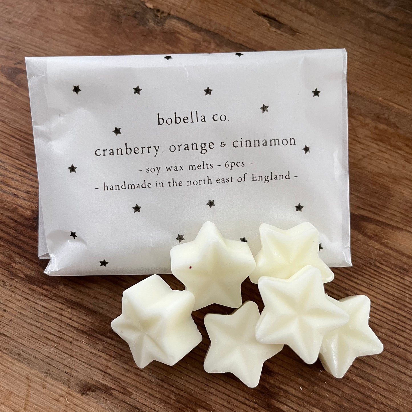 Star-shaped wax melts from bobella co with packaging on a wooden surface