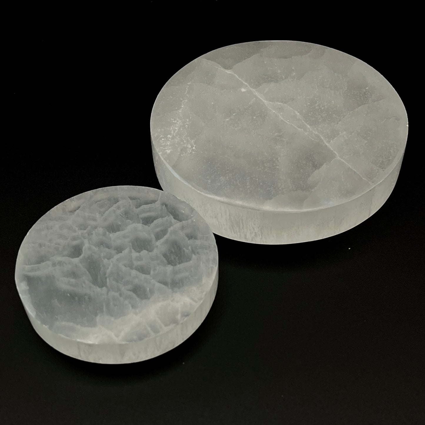 Two round translucent Selenite Crystal slabs with natural crystalline textures, displayed on a solid black background.