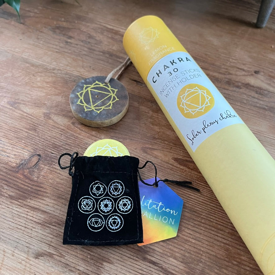 Yellow cylindrical product with label, black drawstring bag, and wooden disc on a wooden surface