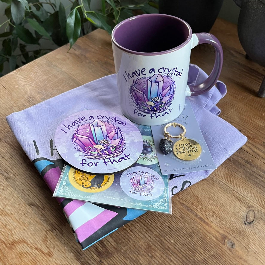 Set of crystal-themed products including a mug, coasters, keychain, and cards on a wooden surface.