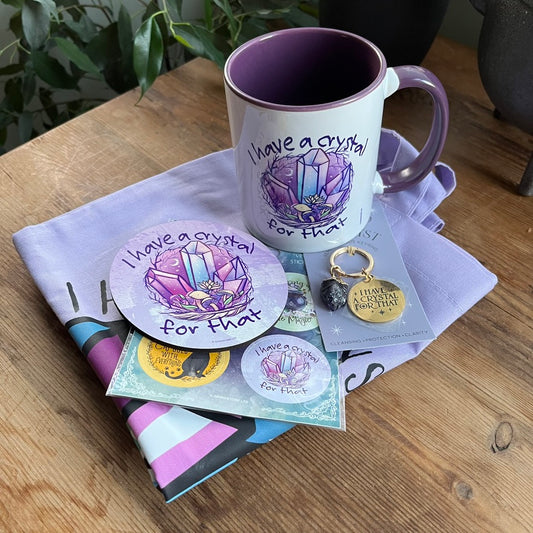 Set of crystal-themed products including a mug, coasters, keychain, and cards on a wooden surface.