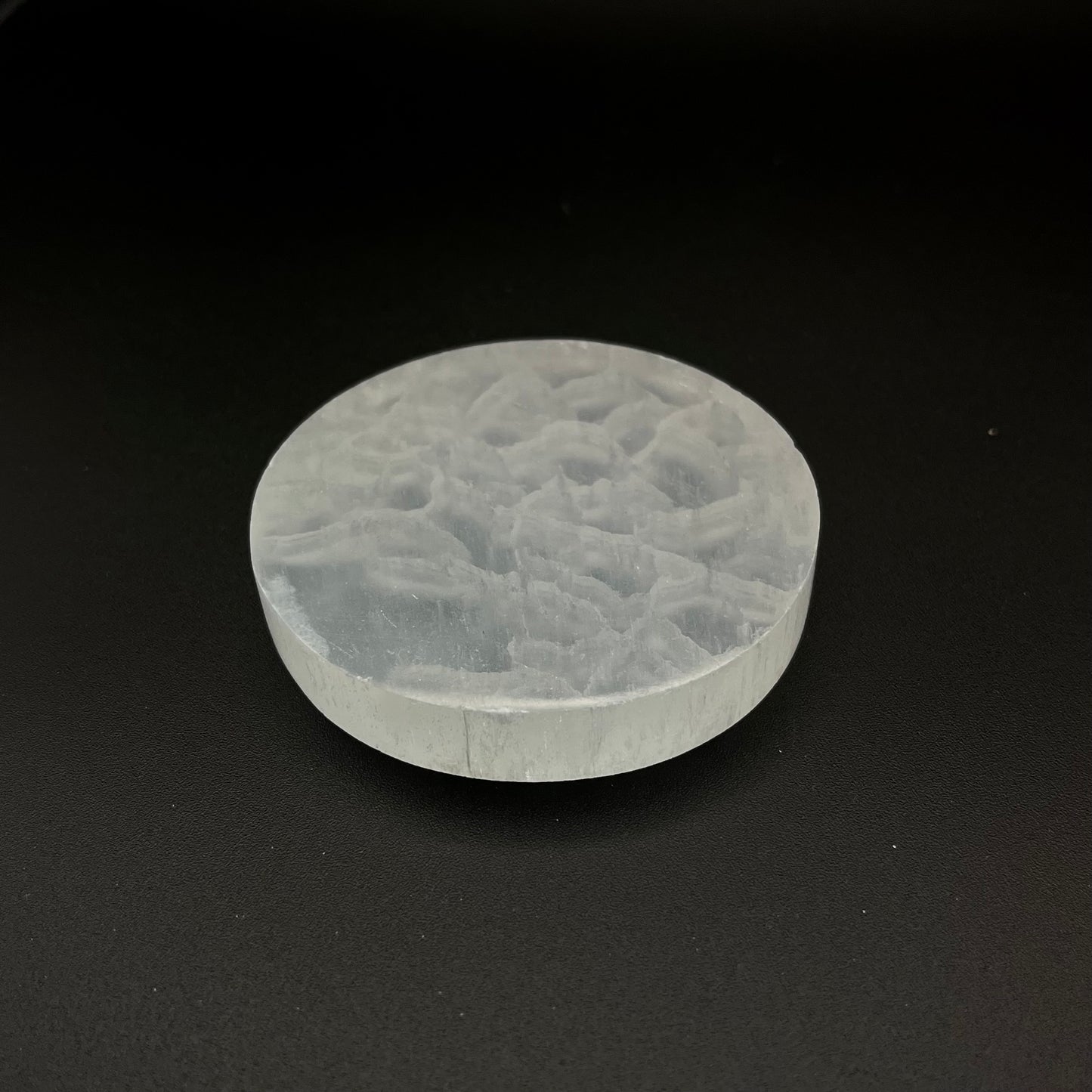 A round, translucent Selenite Crystal Plate shown on a solid black background.