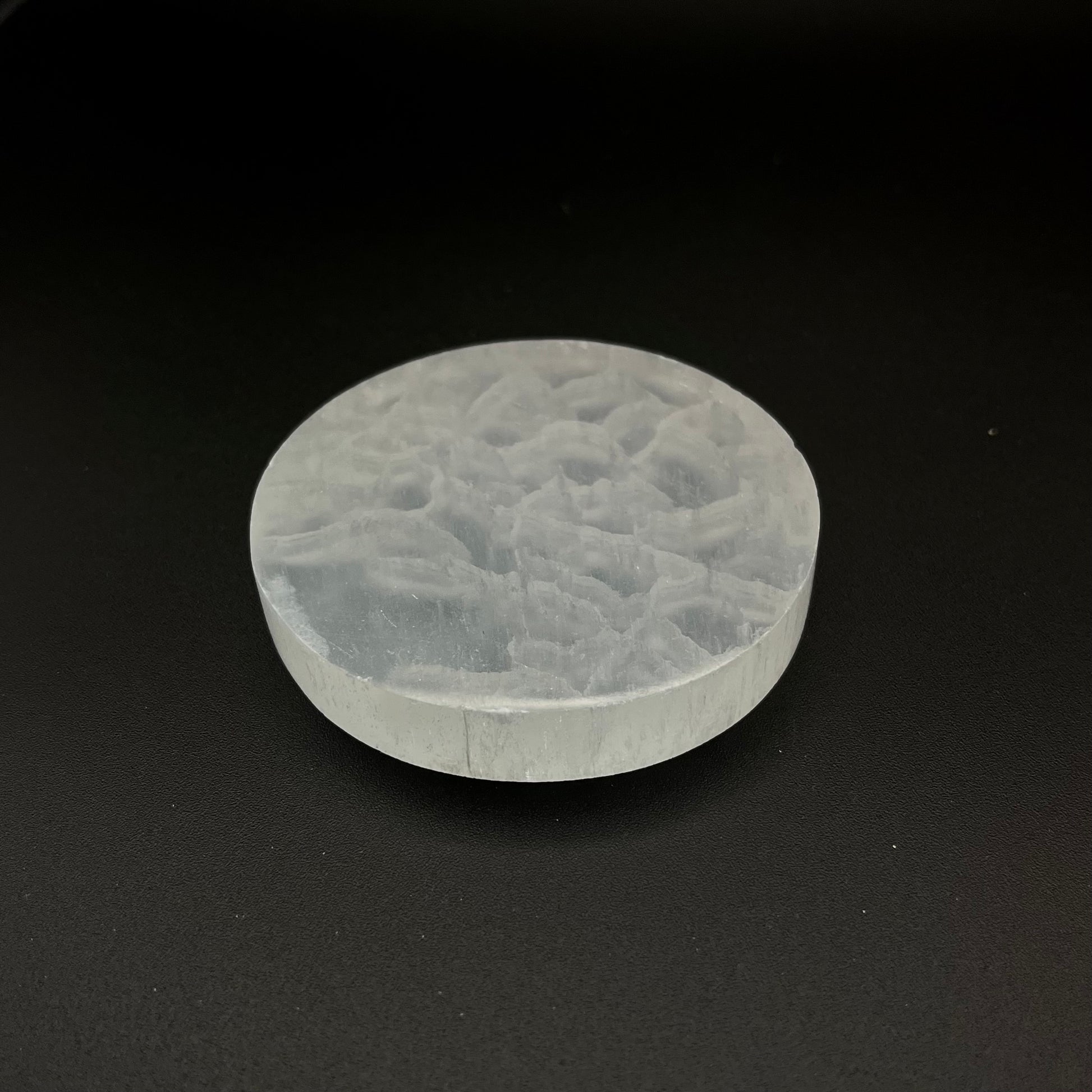 A round, translucent Selenite Crystal Plate shown on a solid black background.