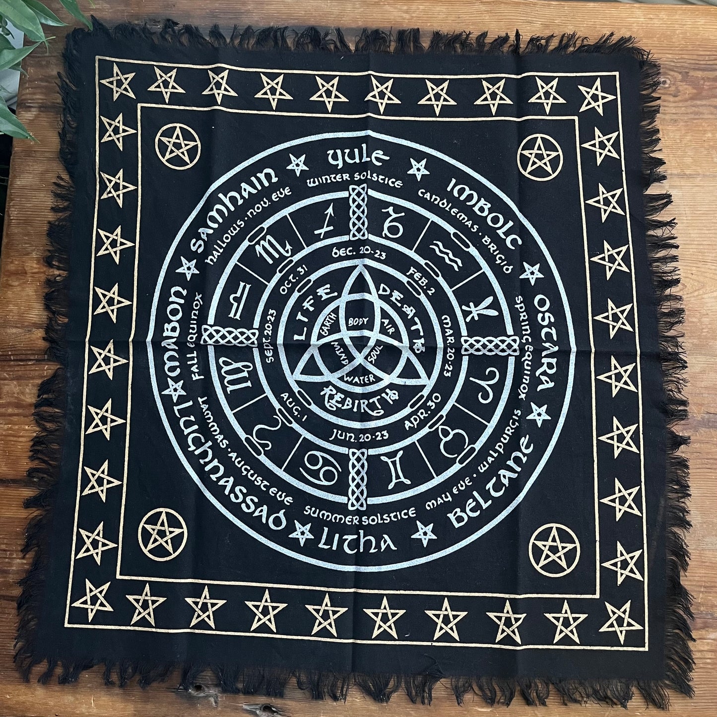 Black square Altar cloth with white Wheel of the Year symbols and text on a wooden surface