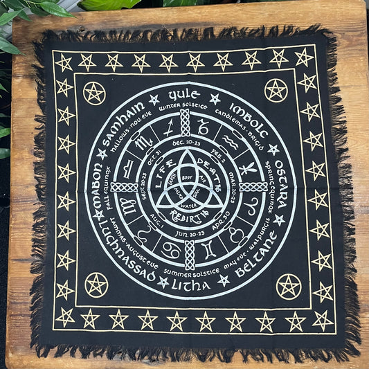 Black square Altar cloth with white Wheel of the Year symbols and text on a wooden surface