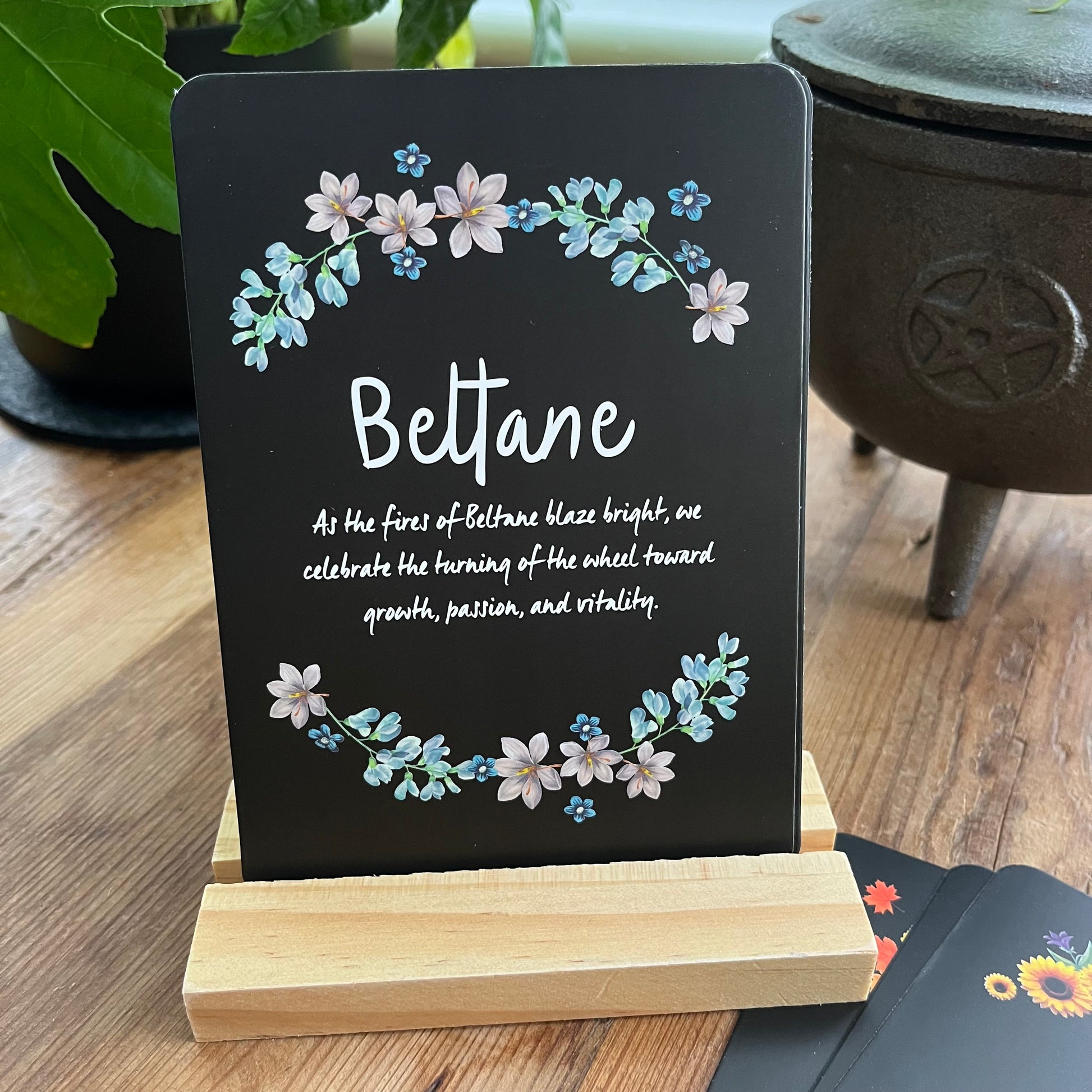 Decorative Altar card with floral design and Beltane text on a wooden stand, placed on a wooden surface.