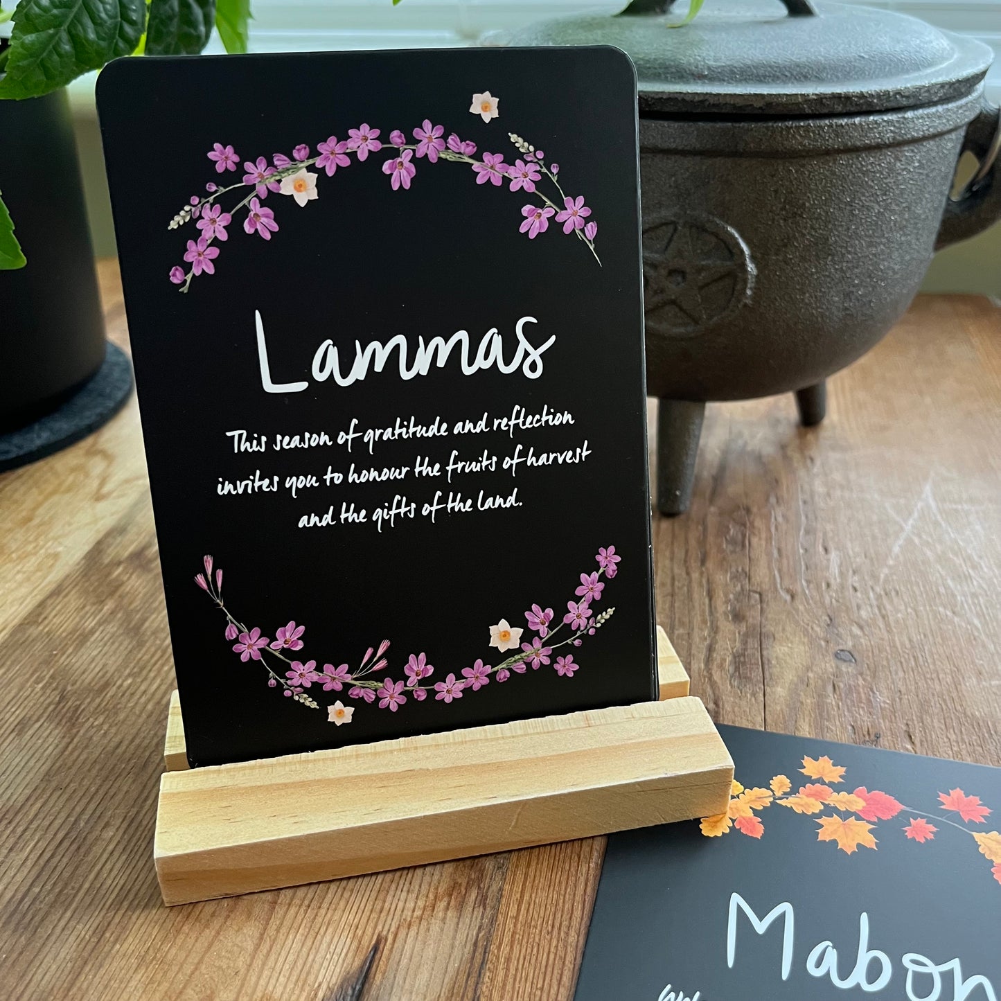 Decorative sign with 'Lammas' text and floral design on a wooden stand.