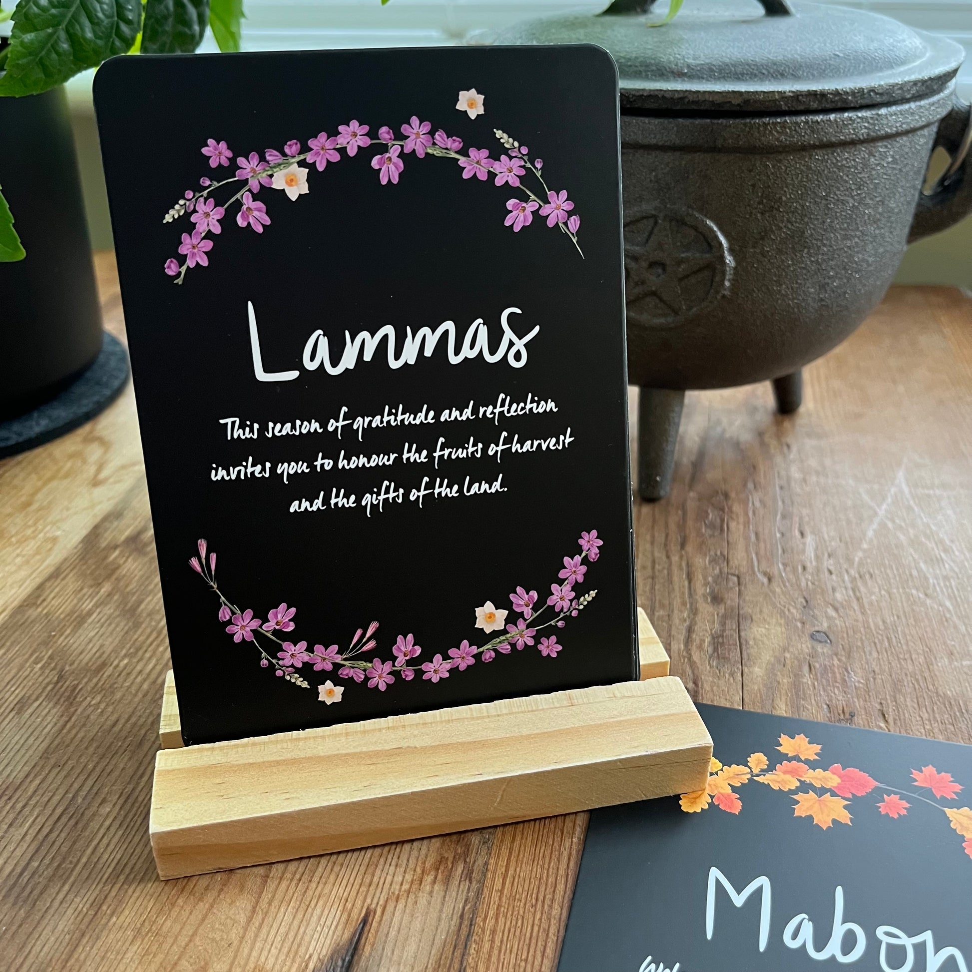 Decorative sign with 'Lammas' text and floral design on a wooden stand.