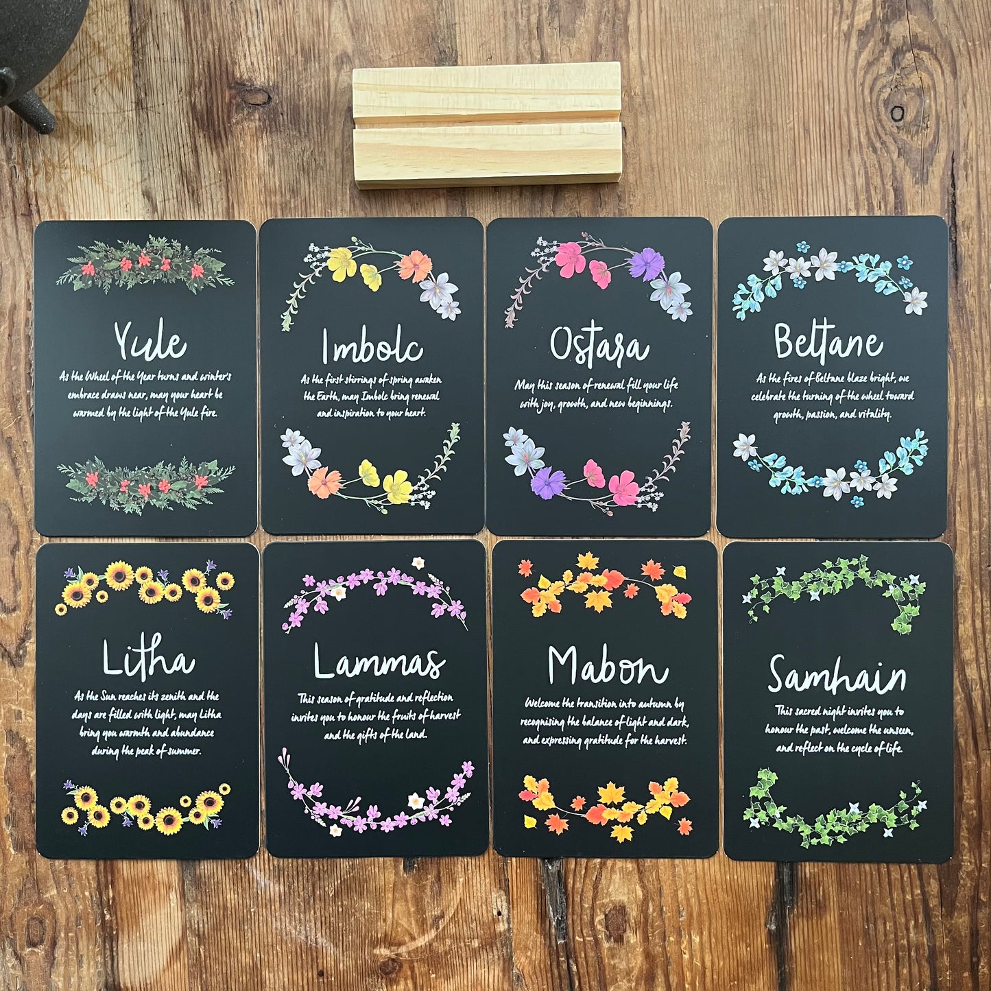 Set of eight Altar cards with floral designs and Sabbat names on a wooden surface