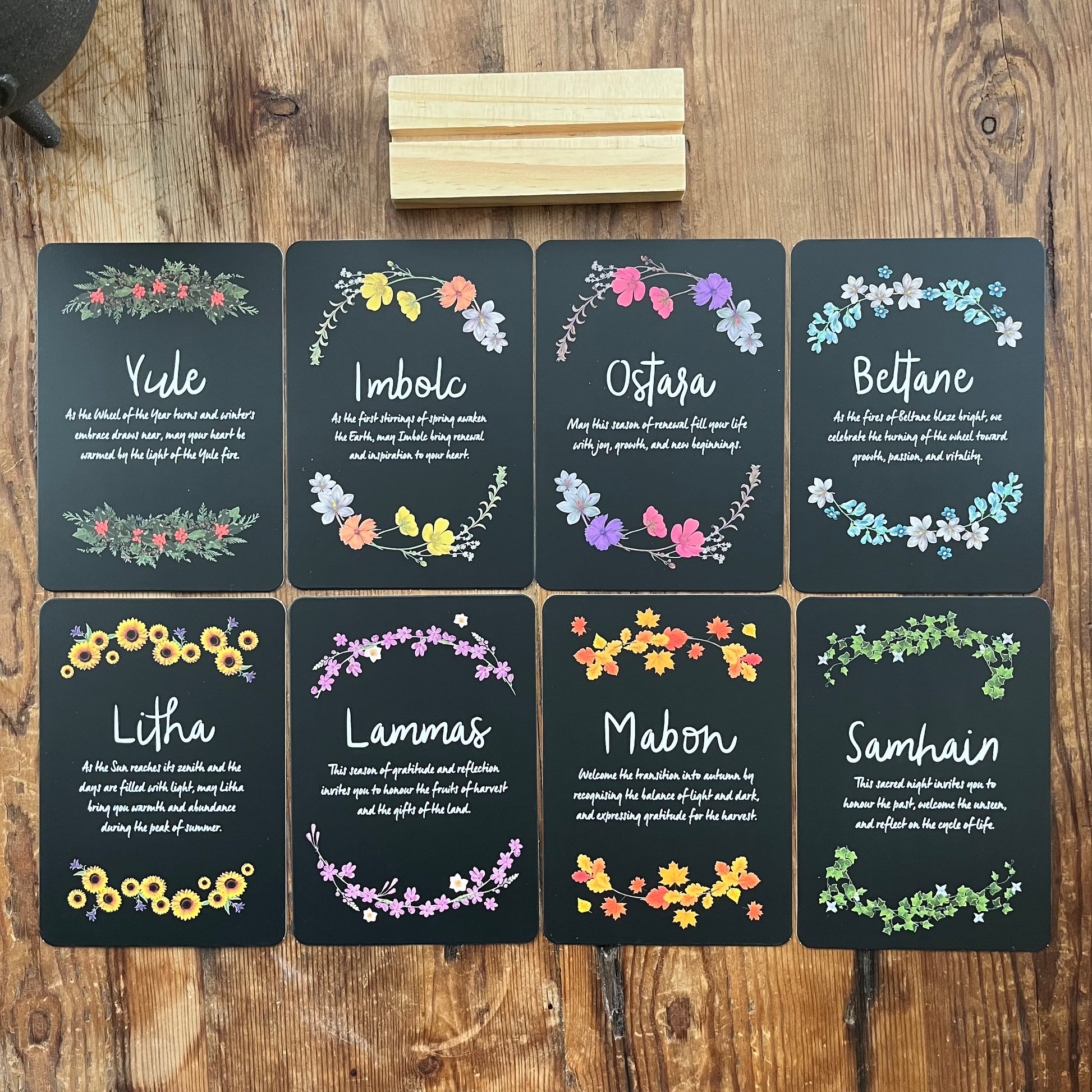 Set of eight Altar cards with floral designs and Sabbat names on a wooden surface