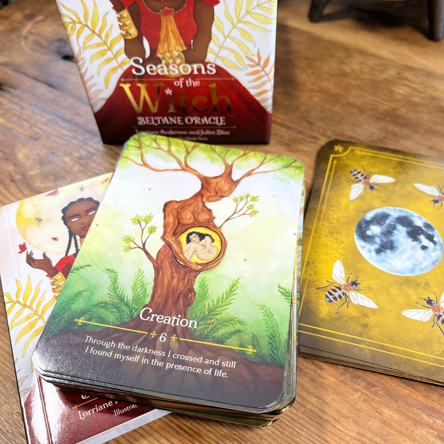 Beltane Oracle card with a tree design and 'Seasons of the Witch' box on a wooden surface