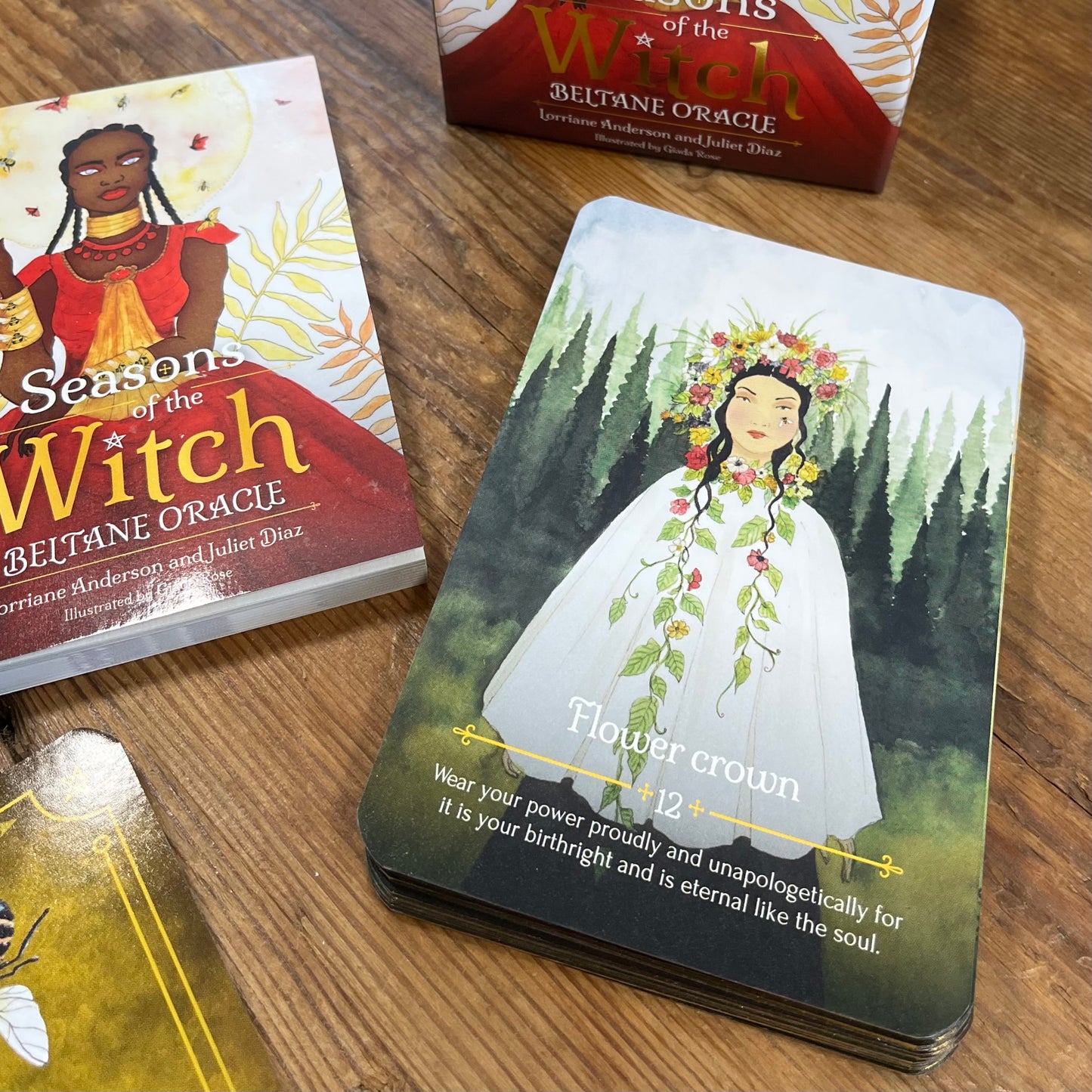 'Seasons of the Witch' Oracle card featuring a woman in a white dress and flower crown on a wooden surface.