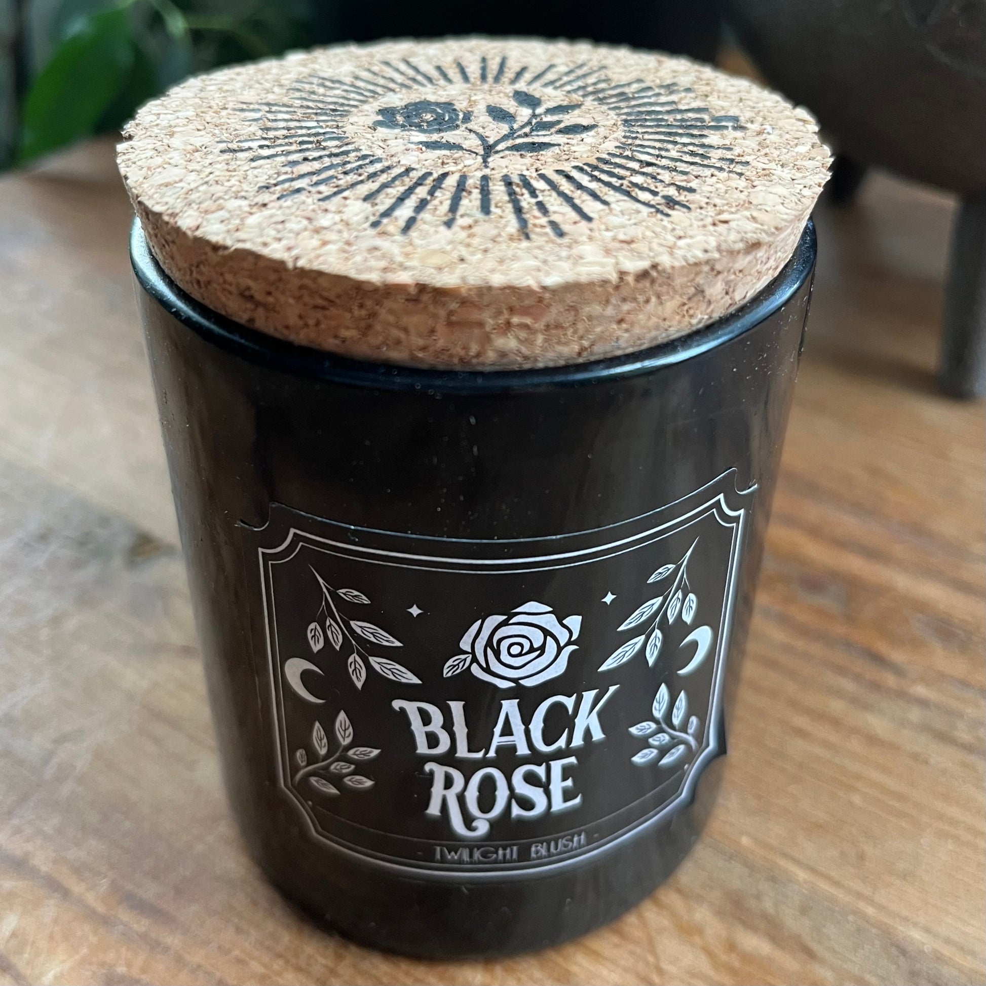 Black Rose candle with cork lid on a wooden surface