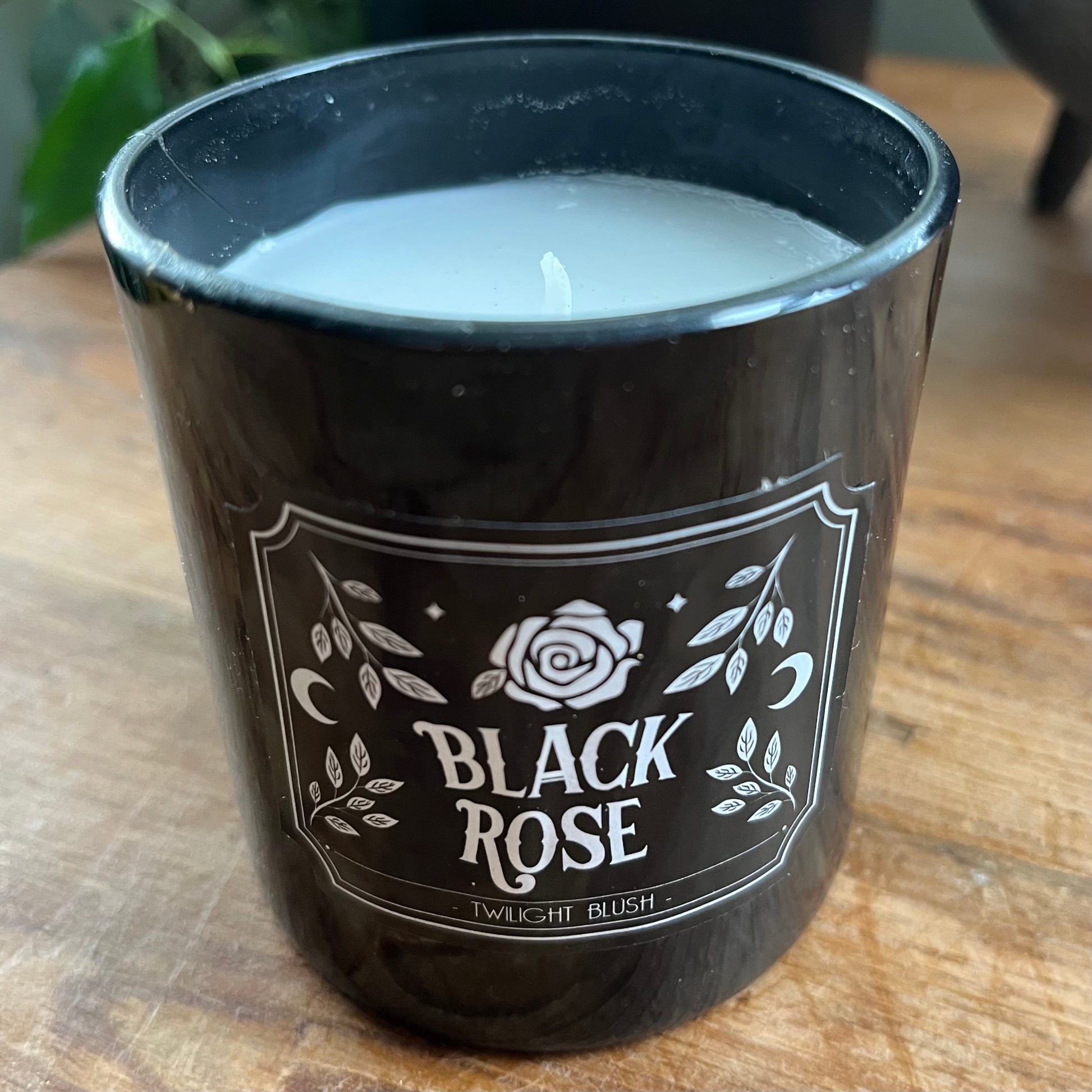 Black candle jar with 'Black Rose' label on a wooden surface