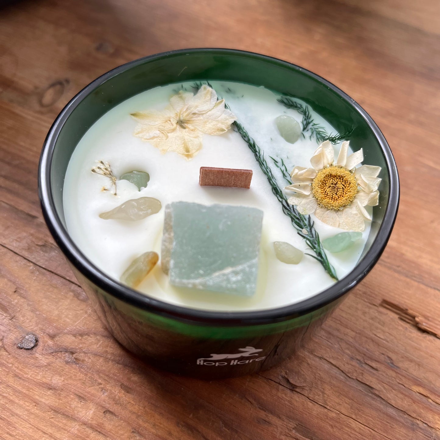 Candle in a green container with decorative elements on a wooden surface