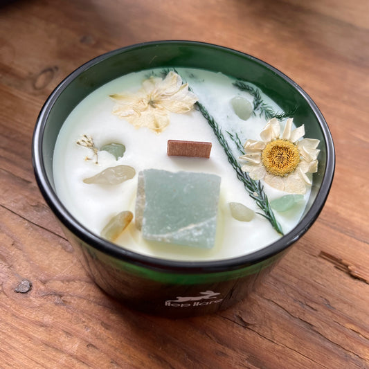 Candle in a green container with decorative elements on a wooden surface