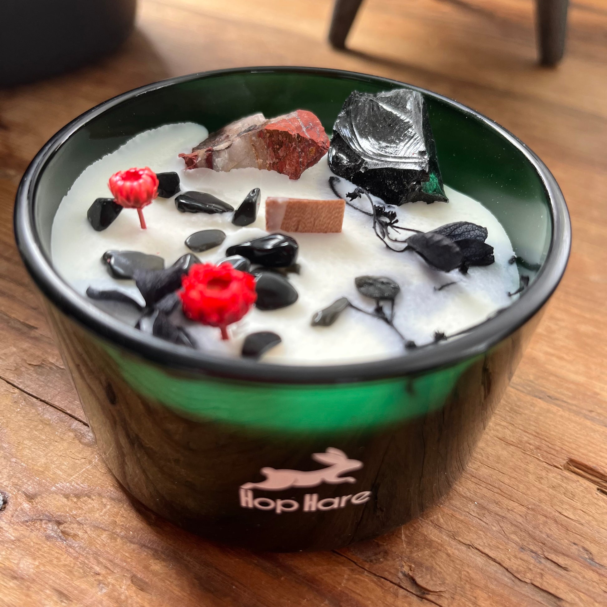 Candle with decorative elements in a green container on a wooden surface