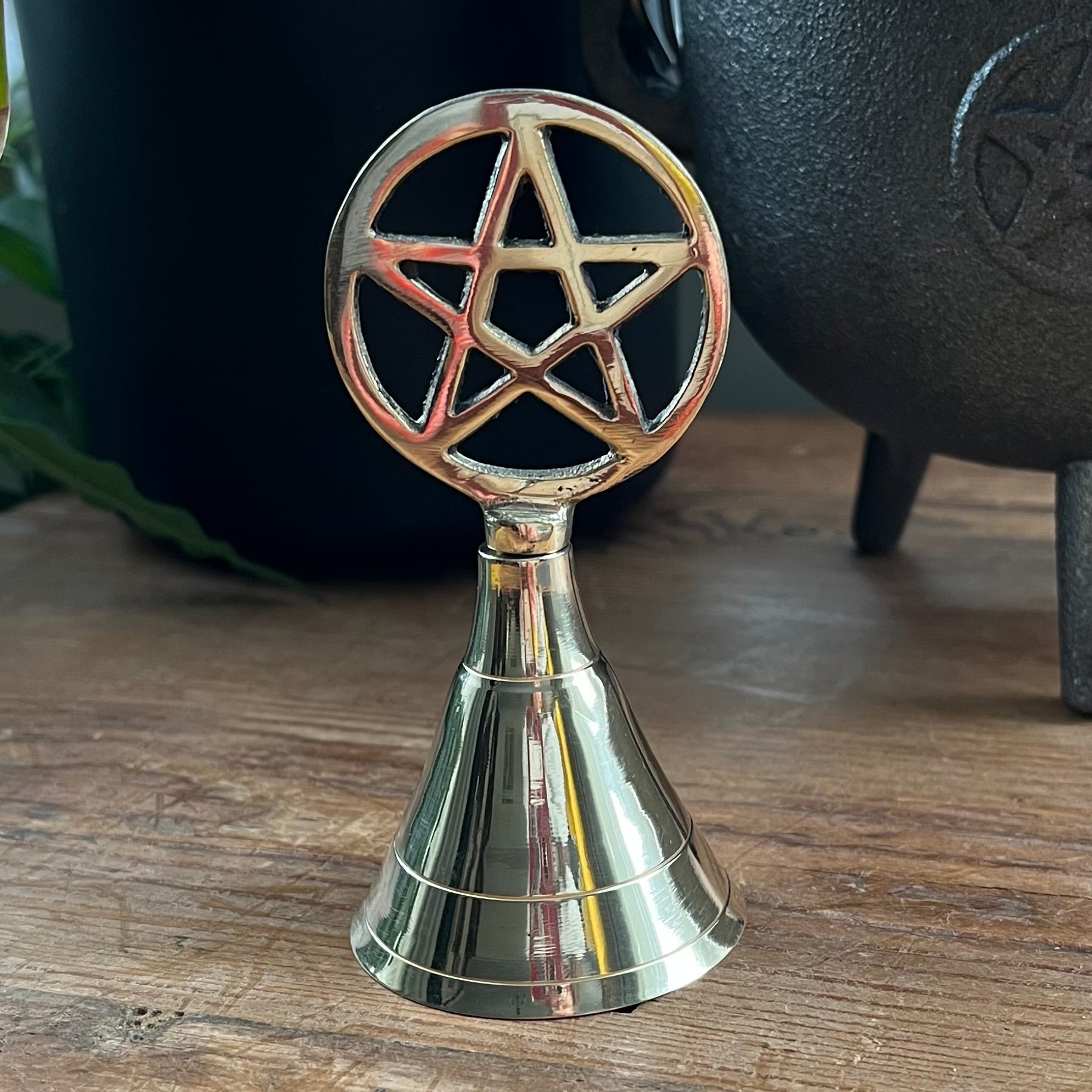 Metallic bell with pentagram design on a wooden surface