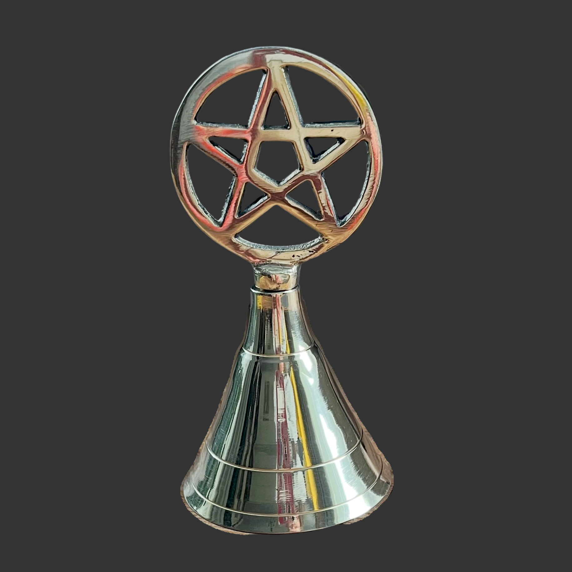 Decorative brass bell with a pentagram design on a black background