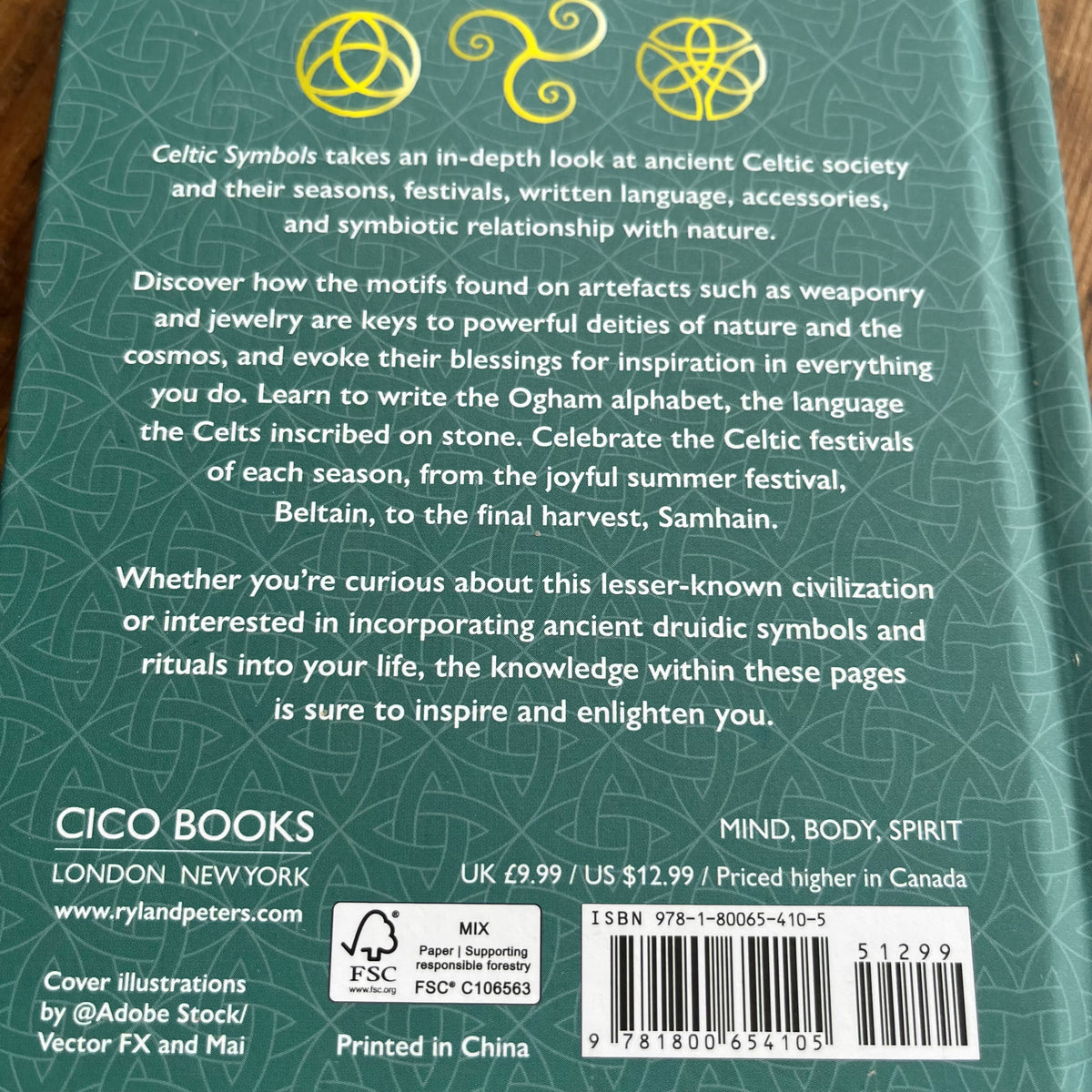 The back cover of the book Celtic Symbols by CICO BOOKS, featuring a dark teal-green background with gold Celtic symbols, a gold-and-white barcode, and white descriptive text.