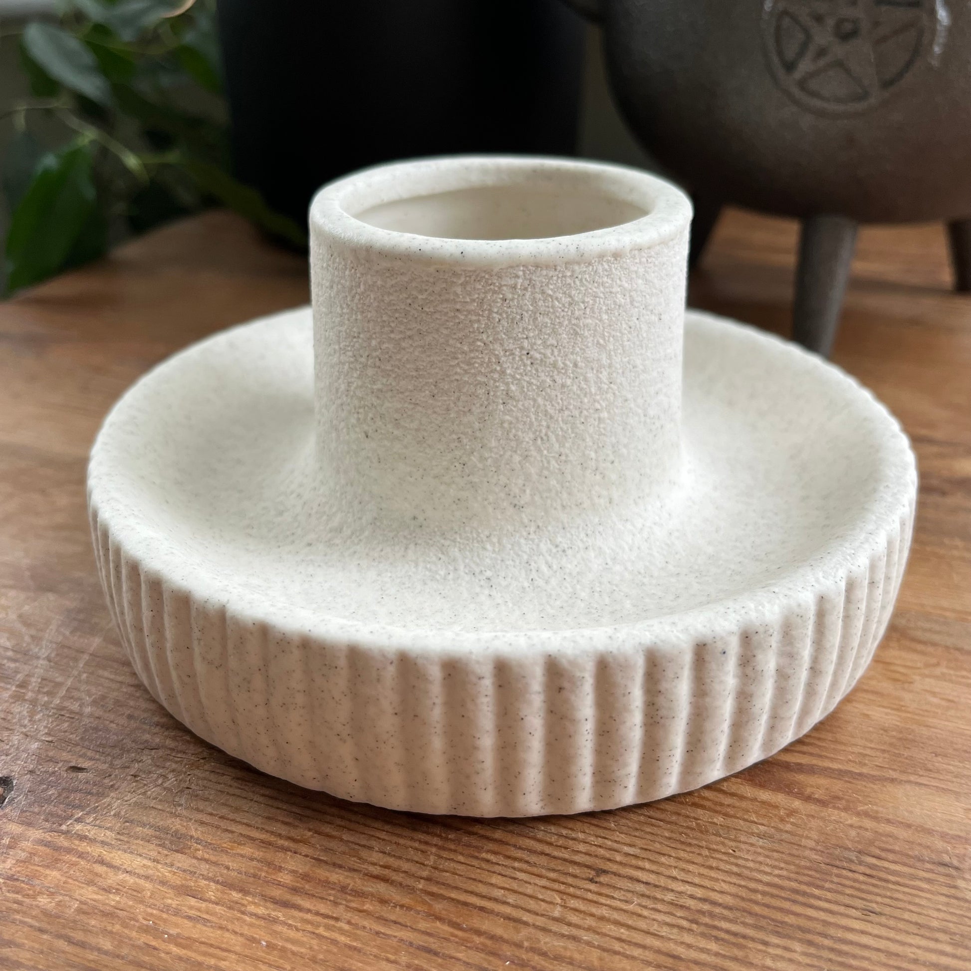 White textured ceramic herb bundle holder / smudge bowl on a wooden surface with a plant and pot in the background