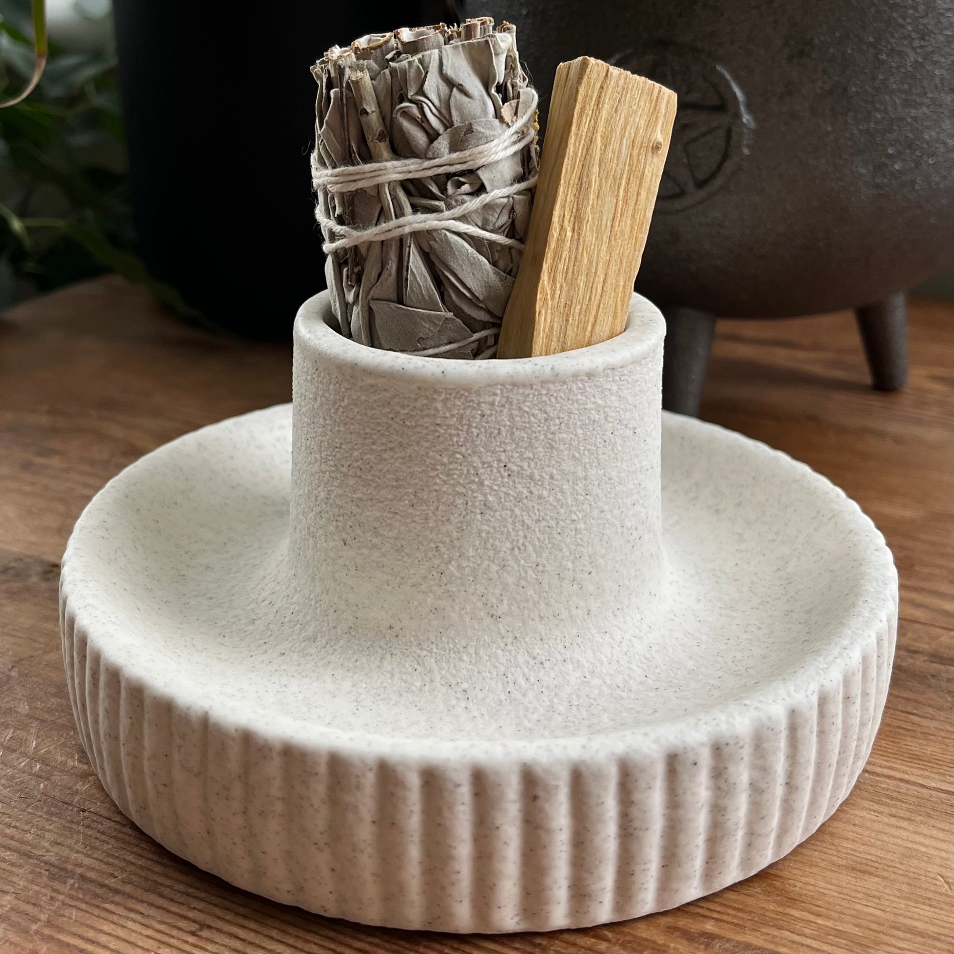 White ceramic holder with smudge sticks on a wooden surface