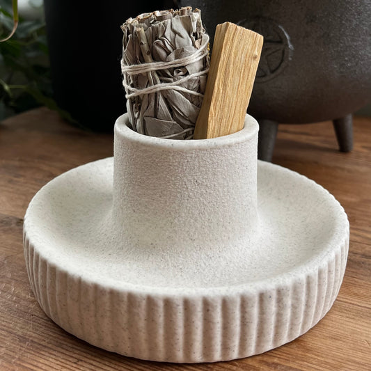 White ceramic holder with smudge sticks on a wooden surface